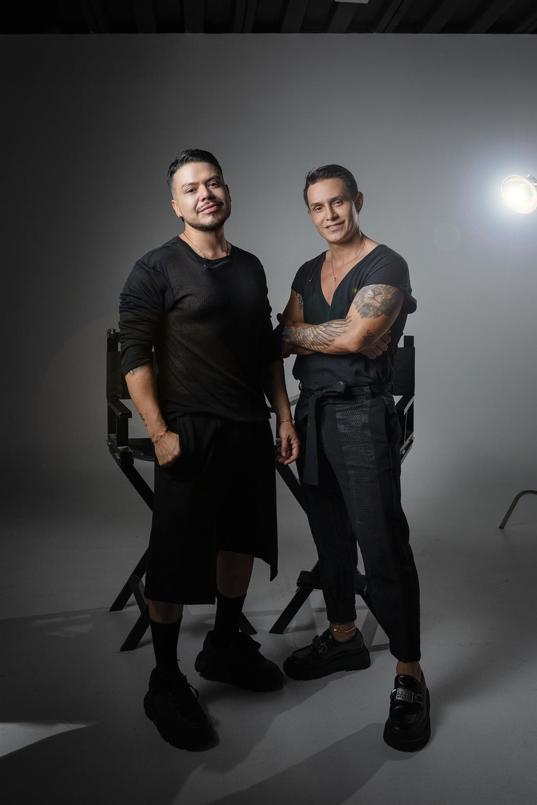 Dos estilistas de Blond vestidos de negro, posando en un estudio fotográfico