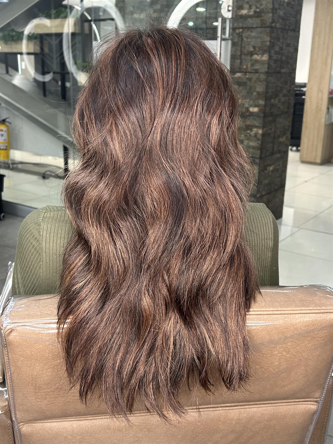 Melena castaña con reflejos en ondas suaves, de espaldas